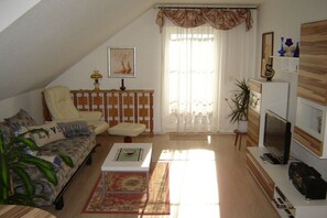 A living room with a sofa, armchair, coffee table, TV, and a plant. - in the Bergblick house (Annaberg-Buchholz OT Cunersdorf)
