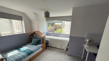 Une petite pièce comprenant un lit superposé, un bureau et une fenêtre donnant sur un espace verdoyant.