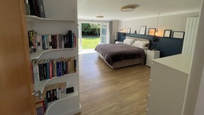 Een slaapkamer met een bed, nachtkastjes, een boekenkast en uitzicht op het buitengebied.