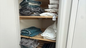 Een kast met planken, met daarin opgevouwen kleding en een label op een van de planken.