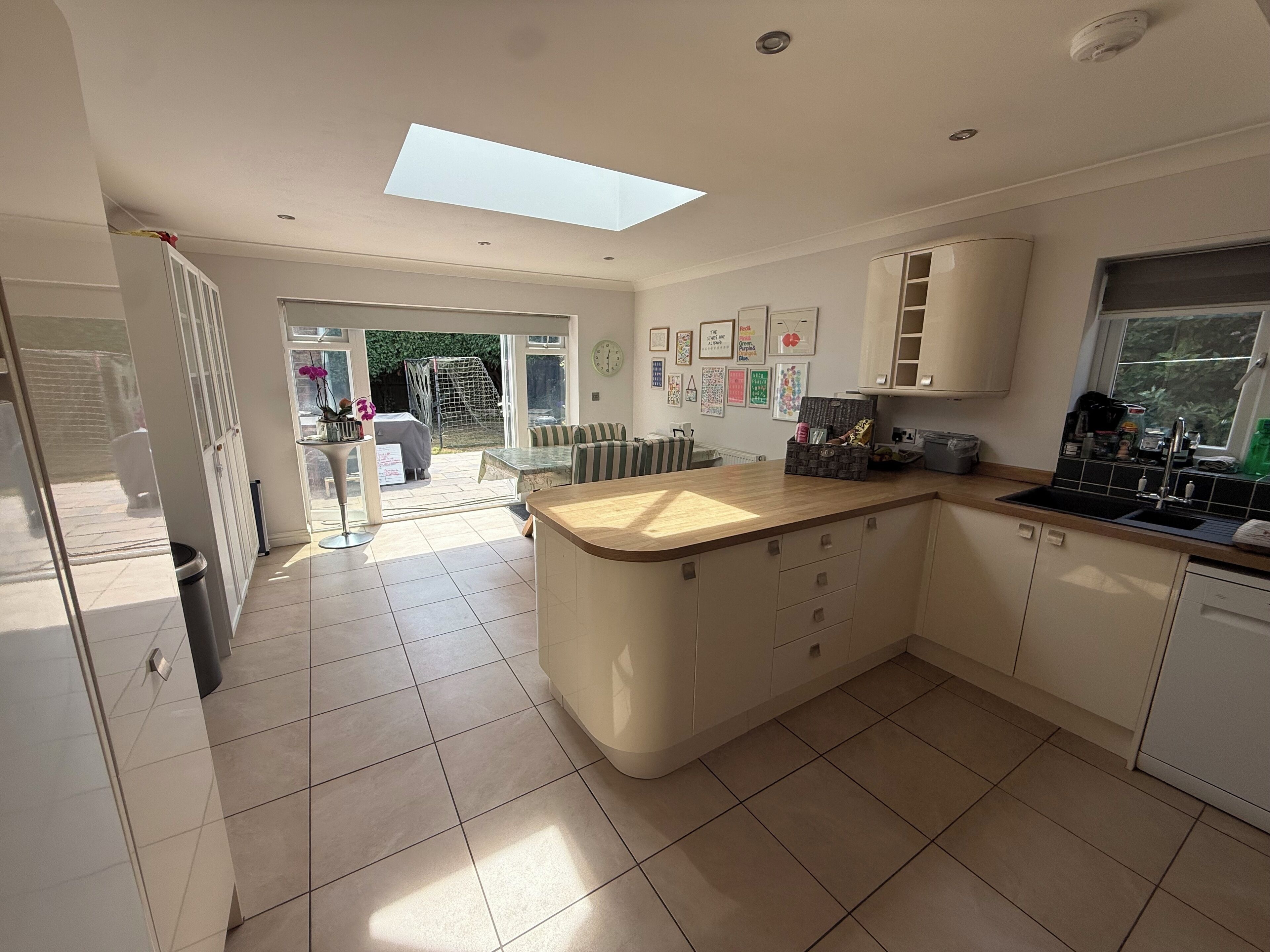 A modern kitchen with a central island, a built-in oven, and a window overlooking a garden.