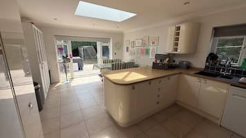 A modern kitchen with a central island, a built-in oven, and a window overlooking a garden.