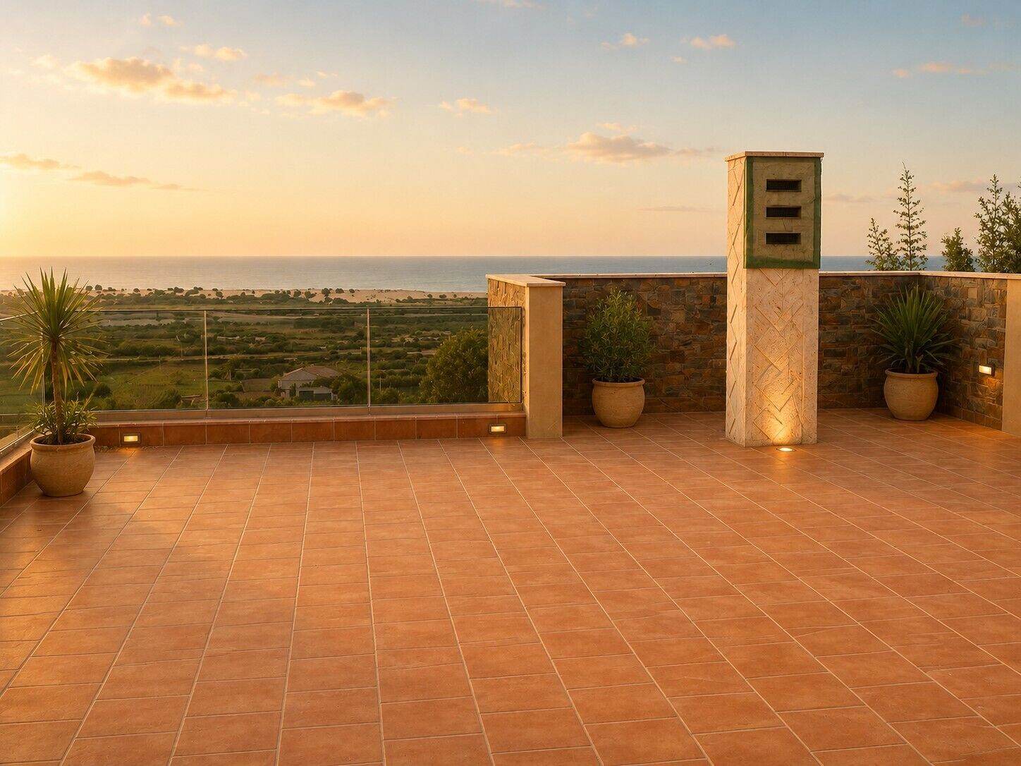 Une terrasse avec vue sur la mer, des plantes en pot et un mur en pierre.