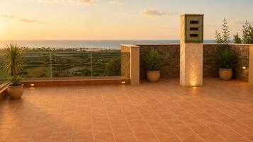 A terrace with a view of the sea, potted plants, and a stone wall.