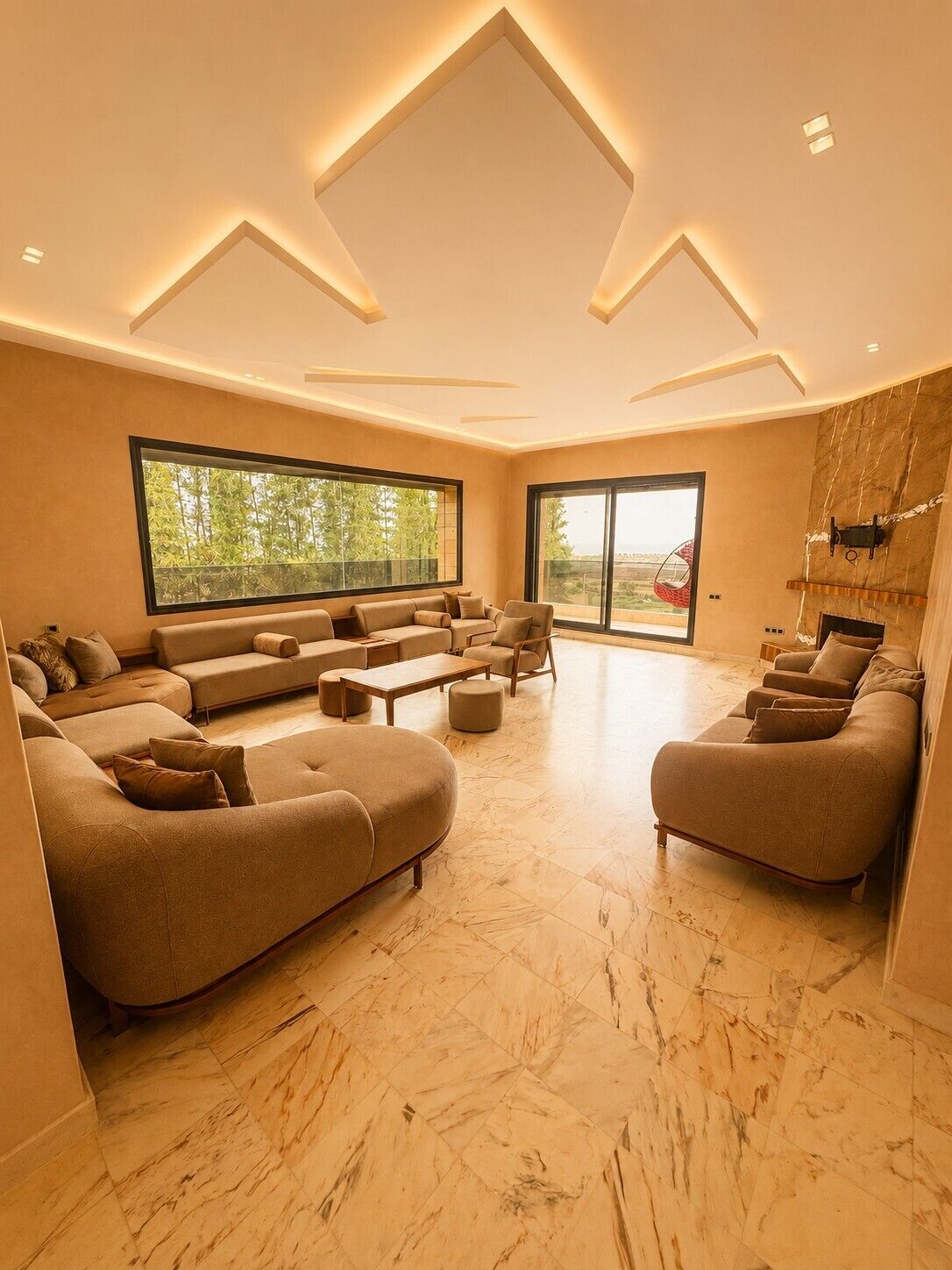 Un salon spacieux doté d’une grande fenêtre, d’une cheminée et d’un design moderne au niveau du plafond.