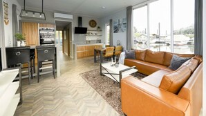 A modern living room with a sofa, a dining area, and a kitchen. - Holiday Home in Olburgen With Terrace (Olburgen)