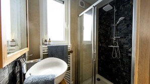 A bathroom with a freestanding bathtub, a glass shower enclosure, and a window providing natural light. - Holiday Home in Olburgen With Terrace (Olburgen)