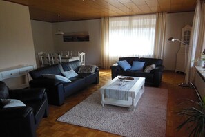 Ein Wohnzimmer mit zwei Sofas, einem Couchtisch und einem Esstisch mit Stühlen.