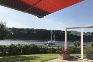 Ein modernes Gebäude mit Glasfassade und Blick auf einen See mit Segelbooten.