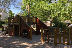 Ein Spielplatz mit Rutsche, Klettergerüst und einer Schaukel aus einem Reifen.