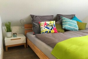 Ein Bett mit mehreren Kissen, ein Nachttisch mit Lampe und ein kleiner Topfpflanze.