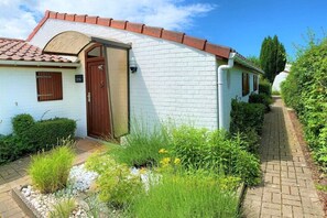 Un edificio blanco con una puerta marrón, una ventana pequeña y un camino que conduce a él.