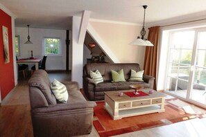 Ein Wohnzimmer mit zwei Sofas, einem Couchtisch und einem Essbereich im Hintergrund.