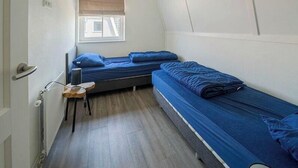 Una habitación pequeña y acogedora con dos camas, una ventana con vistas y un radiador.