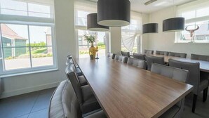 Un comedor moderno con una larga mesa de madera, varias sillas e iluminación colgante.