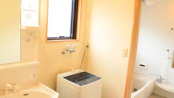 Ein kleines Badezimmer mit Waschbecken, Waschmaschine und Dusche.