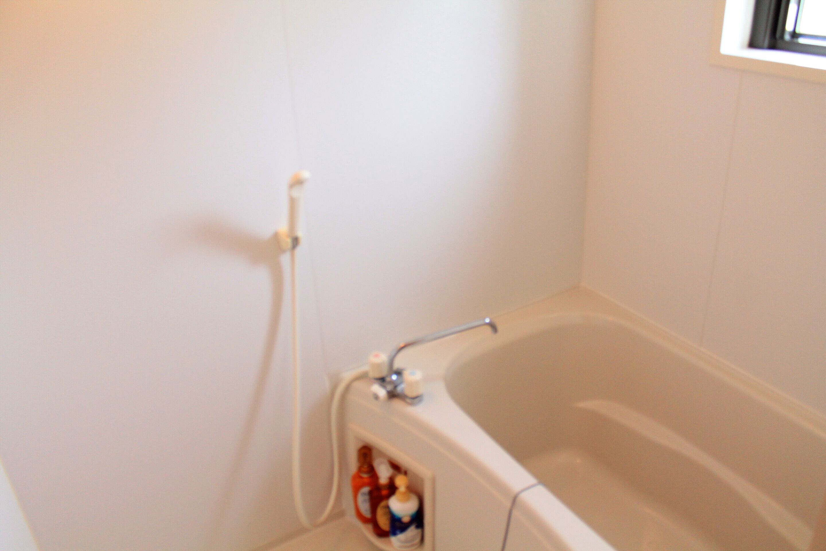 Ein Badezimmer mit einer Badewanne, einer Duschbrause und einer Shampoo-Flasche.