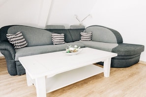 A grey sofa with patterned cushions, a white coffee table, and a small decorative vase. - Holiday apartment with 1 bedroom (Cochem)