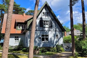 Ein zweistöckiges Haus mit rotem Ziegeldach, weißen Wänden und dunklen Verzierungen.