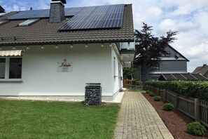 A house with solar panels, a paved driveway, and a fenced yard. - Holiday home with 4 bedrooms (Winterberg)