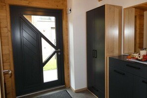 A black door with a glass panel, a wooden cabinet, and a small table with a vase.