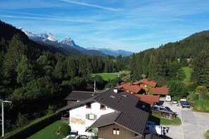 A residential area with houses, a parking area, and a mountainous backdrop.