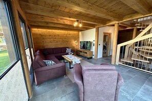 Ein Holzinnenraum mit einer Couch, einem Tisch und einer Treppe.