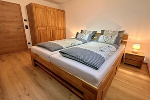 Ein Doppelbett mit Holzrahmen, zwei Nachttische, ein Nachtschrank und ein Kleiderschrank.