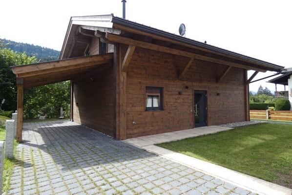 Ein Holzgebäude mit überdachter Veranda, einer Tür und einem kleinen Fenster.