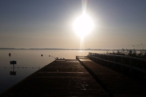 Eine hölzerne Mole, die sich in ruhiges Wasser erstreckt, bewölkter Himmel.