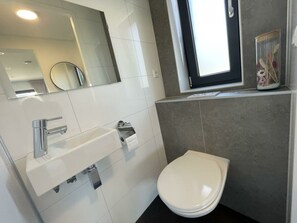 Een moderne badkamer met een wit wastafel, spiegel en toilet.