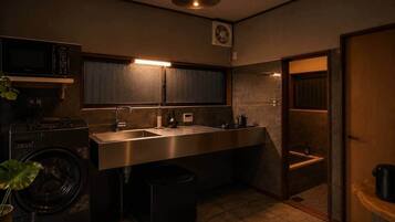 A compact kitchen with a microwave, sink, and a small window.