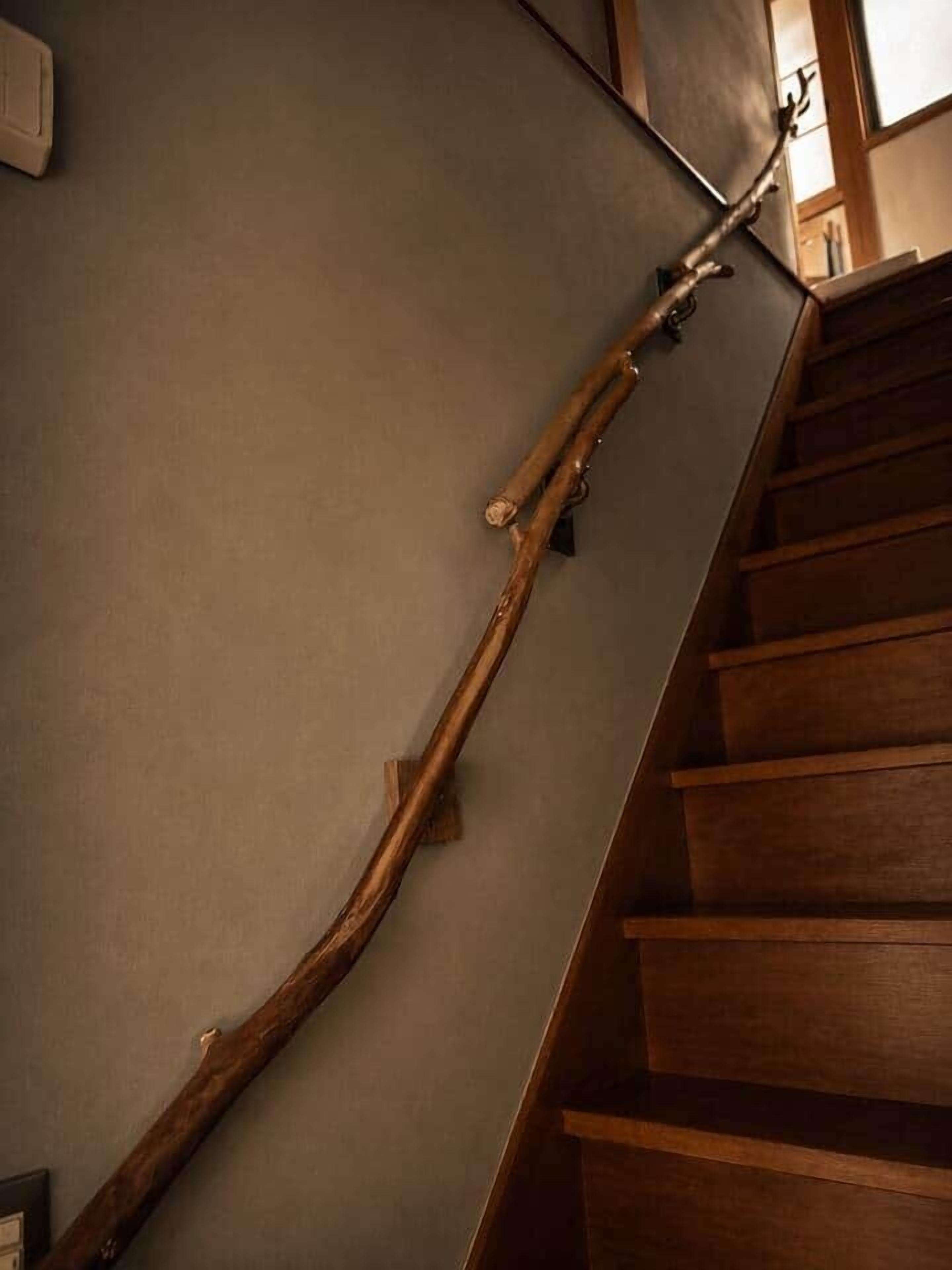 A wooden staircase with a handrail and a wall-mounted light fixture.