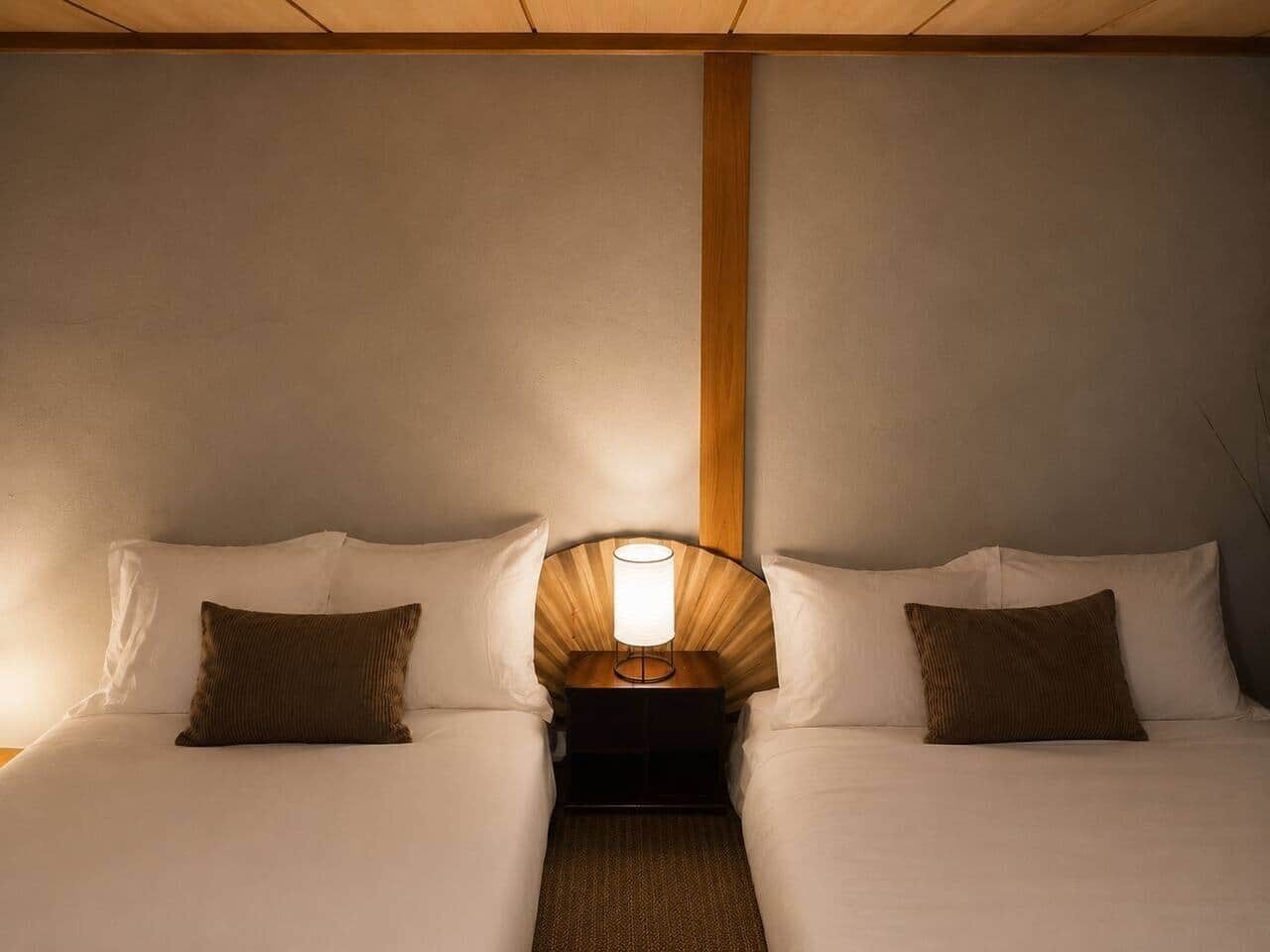 A double bed with a nightstand and lamp between the beds.