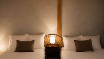 A double bed with a nightstand and lamp between the beds.