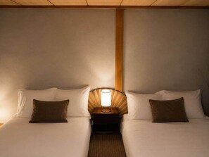 A double bed with a nightstand and lamp between the beds. - Skytree Next Door | Modern Ryokan in Tokyo (Katsushika City)