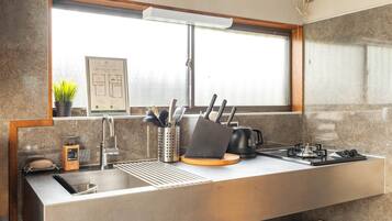 A modern kitchen with a stainless steel sink, a window above the counter, and a fire escape route sign.