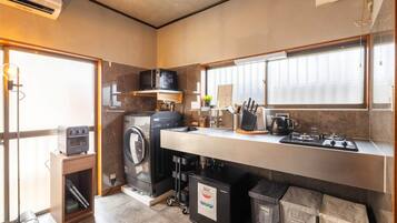 A compact kitchen with a washing machine, microwave, toaster, sink, and a trash bin.