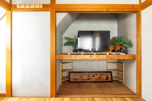 A modern entertainment unit with a flat-screen TV, wooden shelves, and decorative plants.