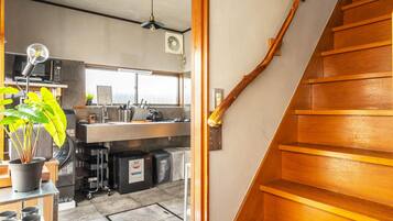 A wooden staircase leading to a kitchen area with a view of the dining space.
