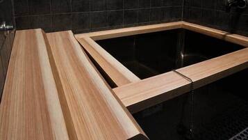 A modern bathroom with a wooden vanity, a black bathtub, and a shower area.