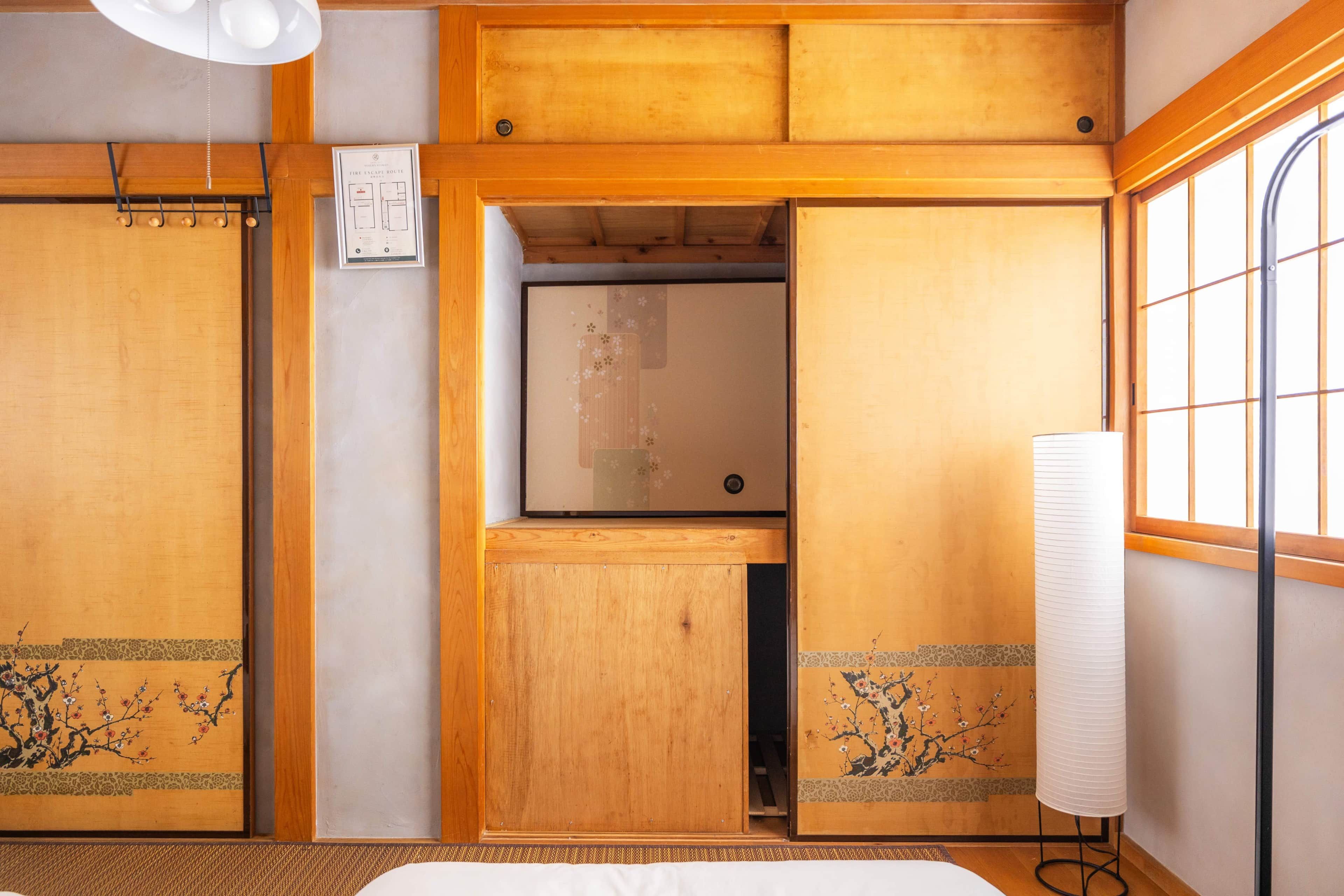 A traditional Japanese-style room with sliding doors, a bed, and a window with a view.
