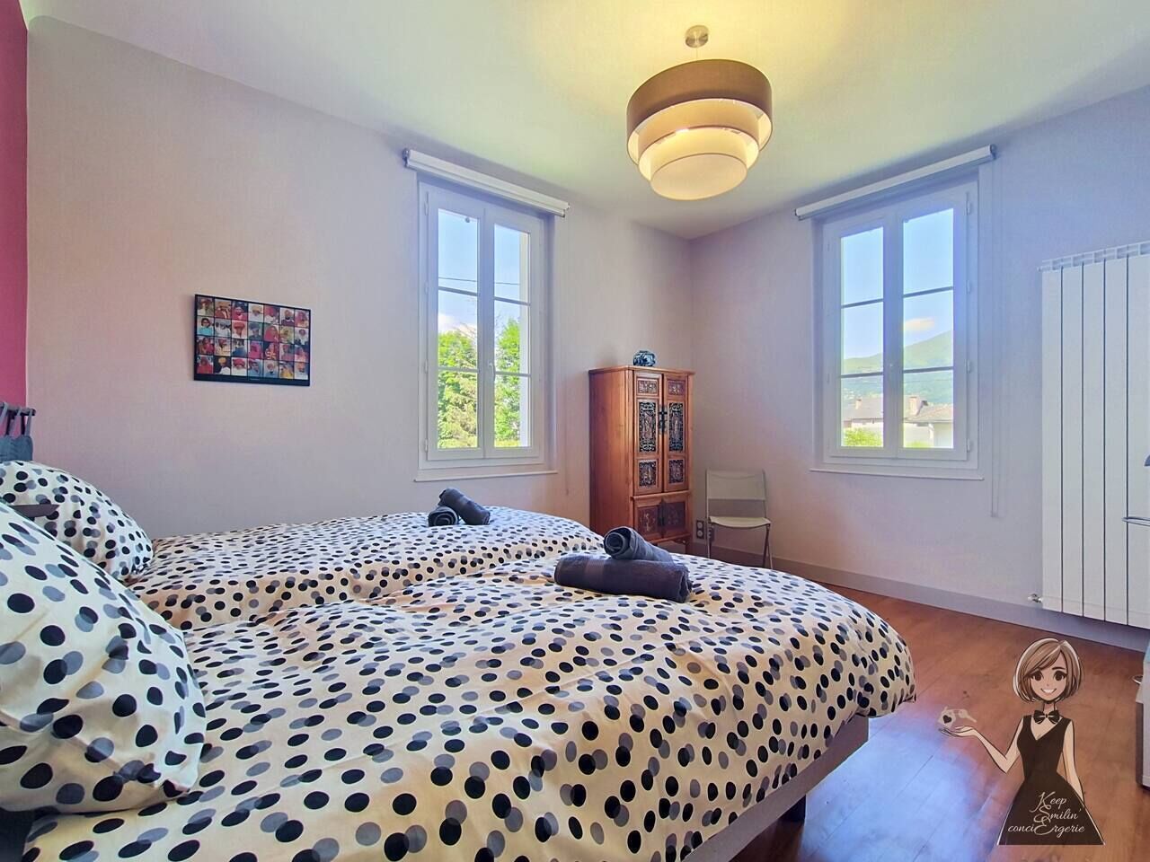 A bedroom with two beds, a wooden cabinet, and a window.