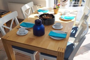 Ein Esstisch mit einer blauen Wasserflasche, Tellern, Tassen und einem Brotkorb.
