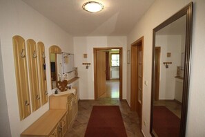 A hallway with a wooden bench, a mirror, and a red carpet. - Alpenrose Leitnerhof (Bad Reichenhall)