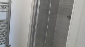 A shower with a glass door and a metal towel rack. - House Sleeps 7 With Garden and Parking (Erith)