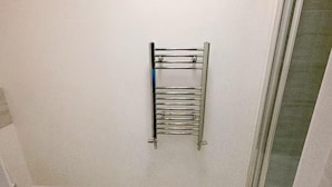 A bathroom with a toilet, a towel rack, and a shower area. - House Sleeps 7 With Garden and Parking (Erith)