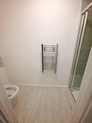 Un baño con inodoro, toallero y zona de ducha.