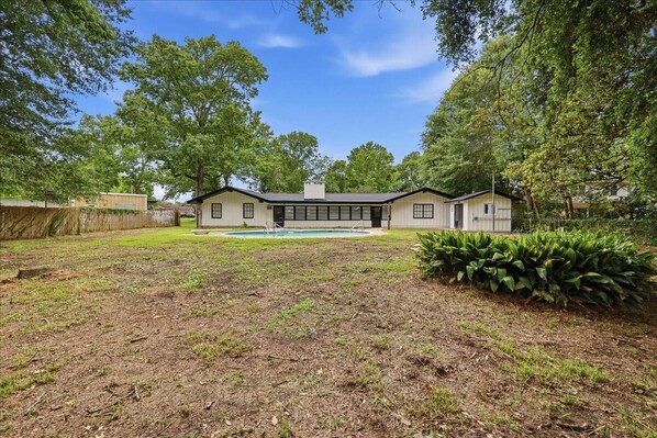 A two-story house with a large front yard, a swimming pool, and a well-maintained lawn.