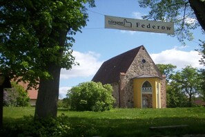 Eine kleine Steinkirche mit gelber Tür und einem Schild darüber.